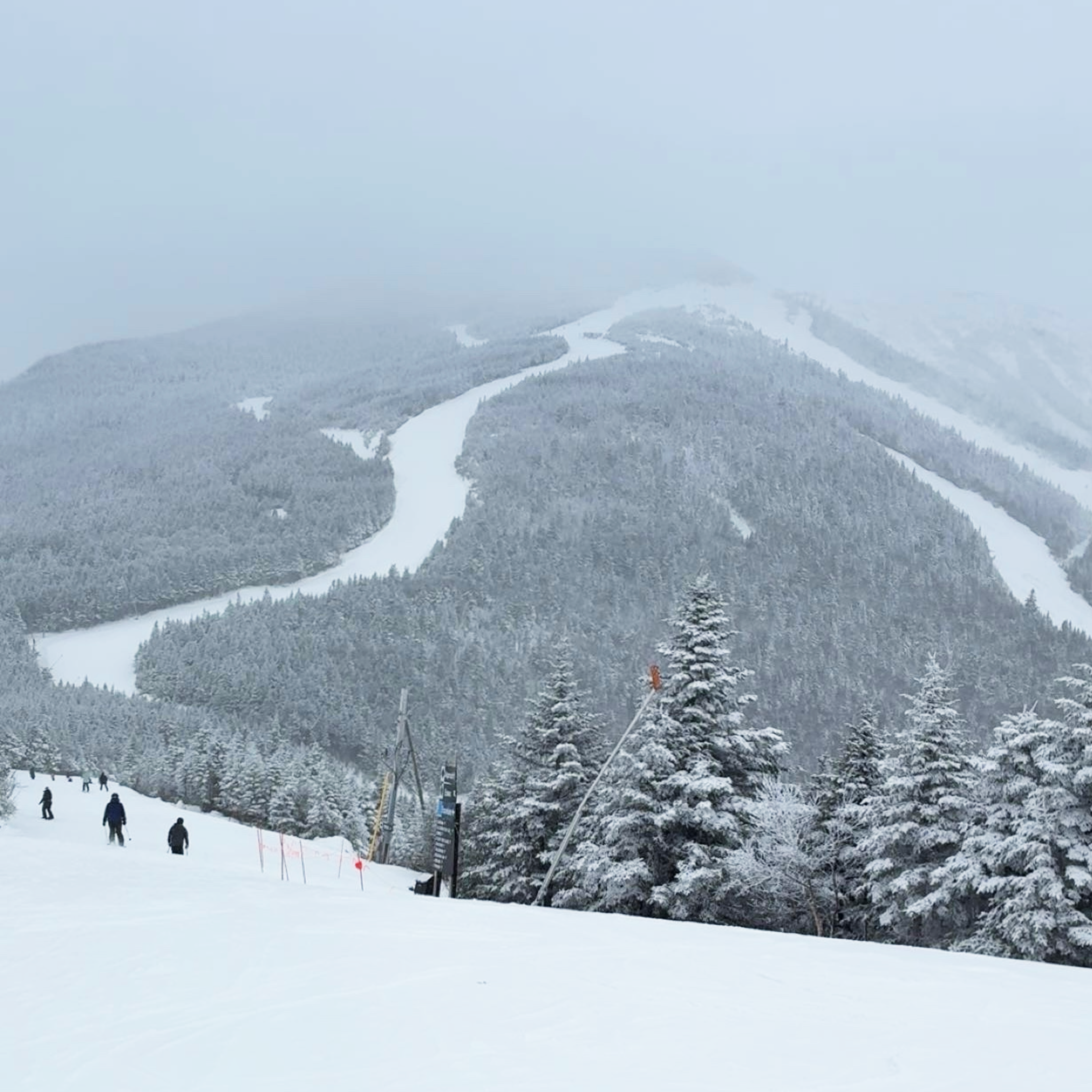 Ski resort with skiers on a snowy slope and a mountain in the background